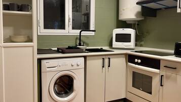 A compact kitchen with a built-in washer, oven, and microwave.