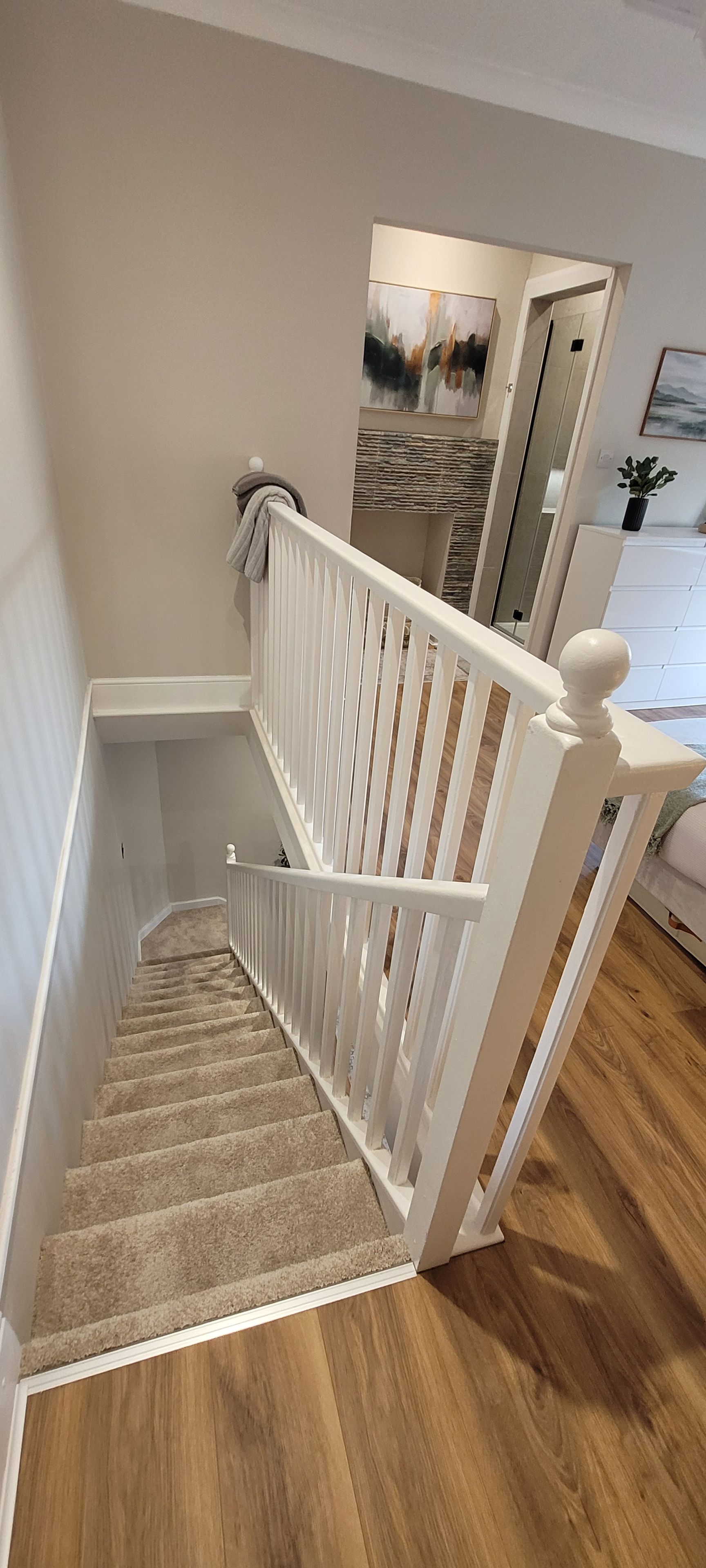 A staircase with white railings and carpeted steps leading to a landing.