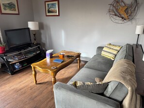 Ett vardagsrum med en soffa, ett soffbord, ett TV-bord med spel och konst på väggen.