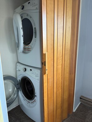 Un lavadero con dos lavadoras apiladas y una puerta de madera.