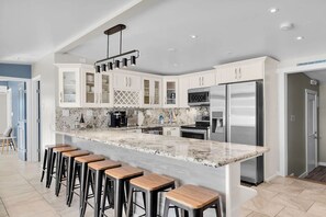 A modern kitchen with a marble countertop, stainless steel appliances, and bar stools. - Pipe Dream - Waterfront + Pool + 120' Dock (Marathon)