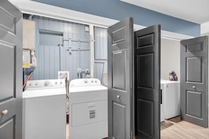 A laundry room with stacked washers and dryers, a water heater, and a blue wall with pipes. - Pipe Dream - Waterfront + Pool + 120' Dock (Marathon)