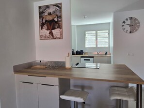 A modern kitchen with a wooden countertop, white cabinets, and a large clock on the wall. - Azure Ti Briz (Les Trois-Îlets)