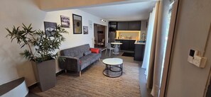 Ein Wohnzimmer mit einer Couch, einem kleinen runden Tisch und einem Blumentopf.