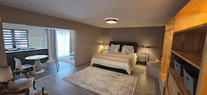 Quarto com cama, mesas de cabeceira, escrivaninha e uma cadeira.