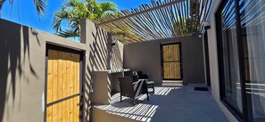 Uma área de estar moderna ao ar livre, com pérgola, móveis confortáveis e vista para palmeiras.