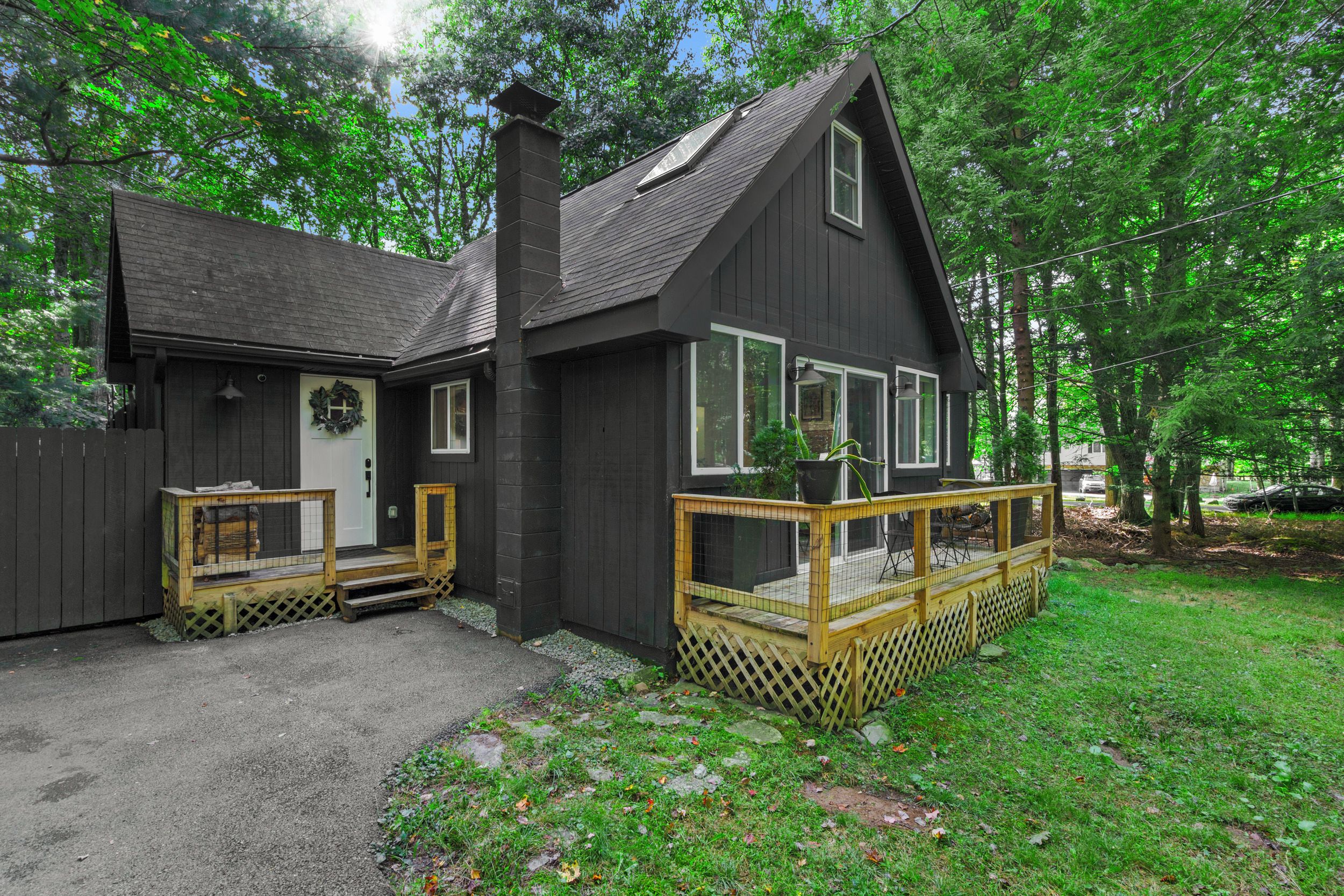 A two-story cabin with a porch, a chimney, and a deck.