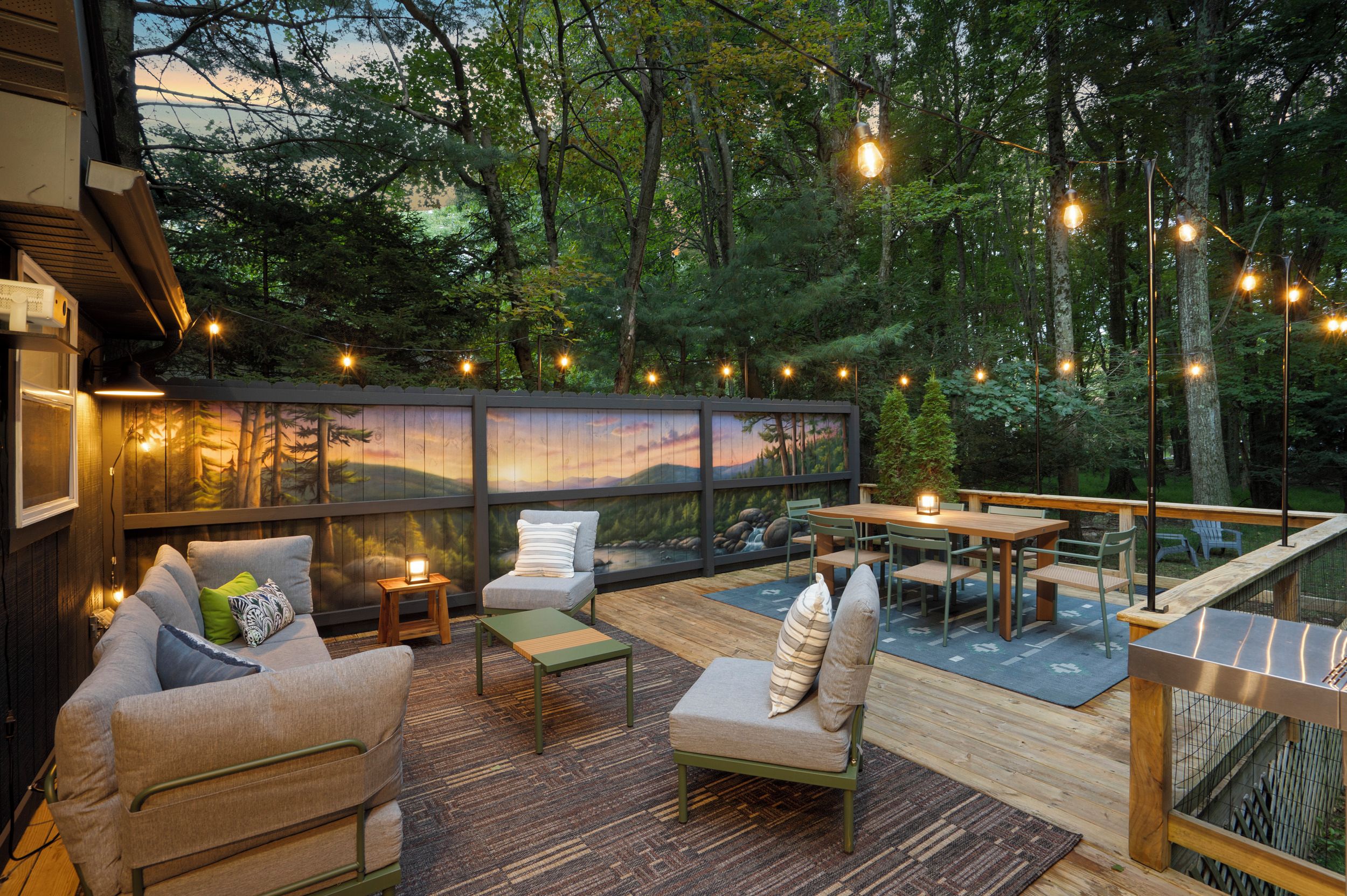 Eine Terrasse im Freien mit Sitzgelegenheiten, einem Esstisch und Lichterketten.