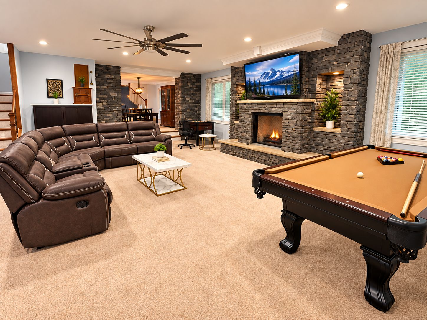 A living room with a pool table, a leather sectional sofa, a flat-screen TV, and a stone fireplace.