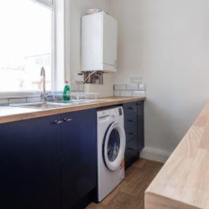 A compact kitchen with a built-in washing machine, a window with a view, and a countertop. - Stockton-on-tees - Sleeps 4 - Near Norton Village (Stockton-on-Tees)