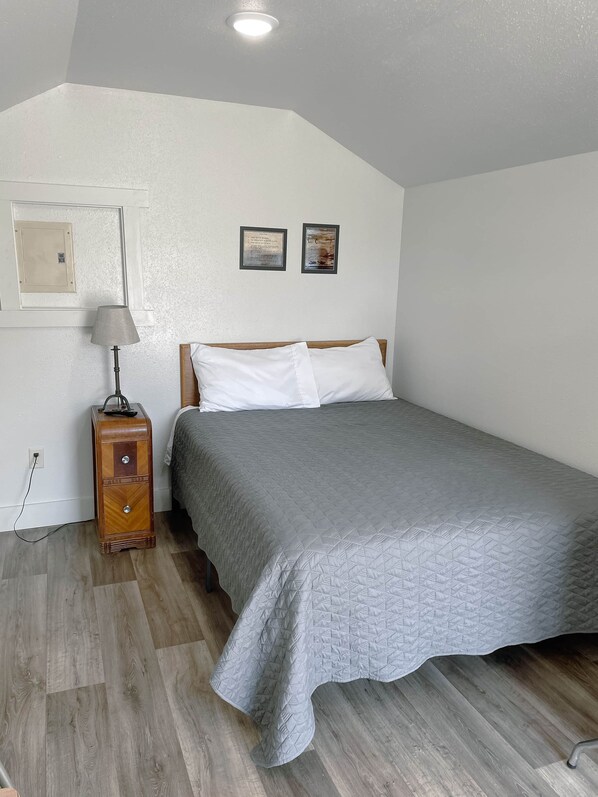 A bedroom with a bed, a nightstand, a lamp, and two framed pictures on the wall.
