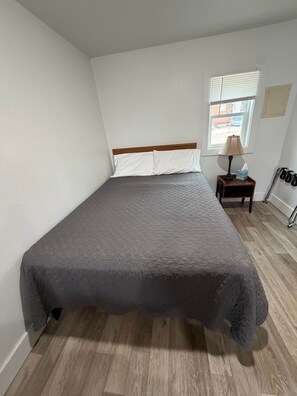 A bedroom with a bed, a nightstand, a window, and a wall-mounted coat rack.