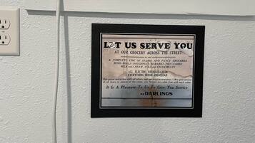 Un climatiseur mural, doté d’un panneau de commande et d’une enseigne publicitaire pour des services d’épicerie.