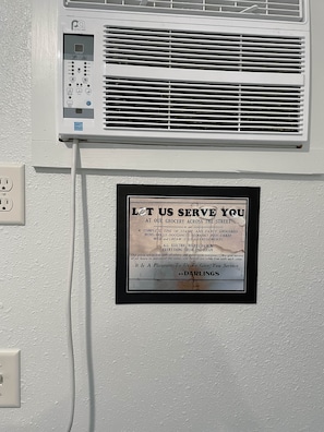 Eine wandmontierte Klimaanlage mit Bedienfeld und einem Schild, das Lebensmittelgeschäfte bewirbt.