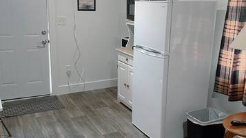 Une petite cuisine équipée comprenant un réfrigérateur, un four à micro-ondes et un petit placard.