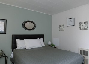 A bedroom with a bed, a round mirror, and several framed pictures on the wall.