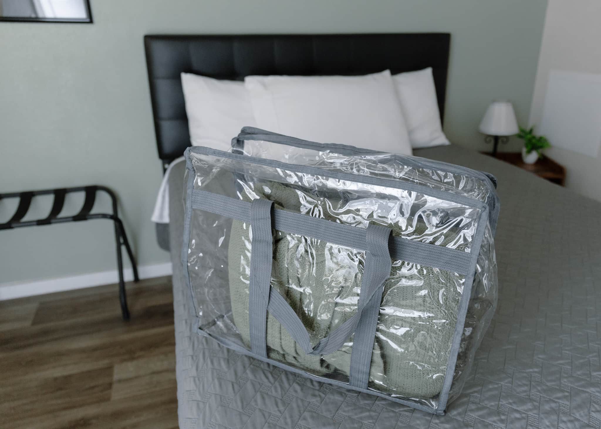 A bed with a grey quilt and a black headboard in a room with a wooden floor.