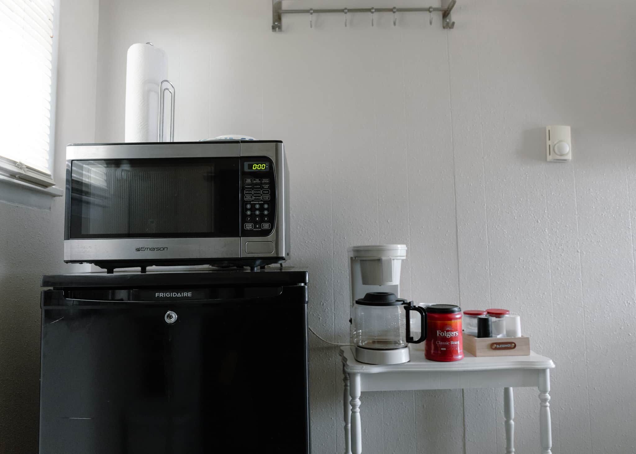 A compact kitchenette with a microwave, coffee maker, and storage containers.