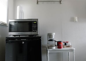 Une petite cuisine équipée d’un four à micro-ondes, d’une machine à café et de récipients de rangement.