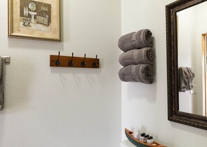 Ein Badezimmer mit Holzhandtuchhalter, Spiegel und Waschbecken mit Pflegeartikeln.