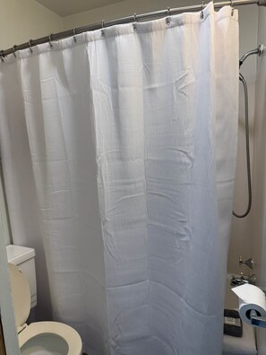 A bathroom with a shower curtain, toilet, and a towel rack.