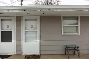 Une maison avec deux portes de garage, dont l’une porte un panneau « Il est interdit de fumer », et une petite table à l’extérieur.