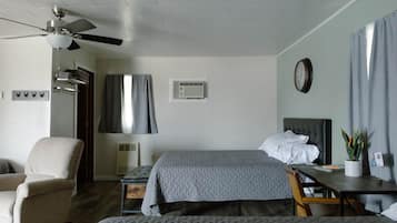Une chambre d’hôtel avec deux lits, une chaise, un bureau, un ventilateur de plafond et un appareil de climatisation.