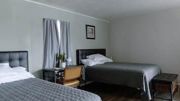 A hotel room with two beds, a desk, a chair, a potted plant, and a framed picture on the wall.
