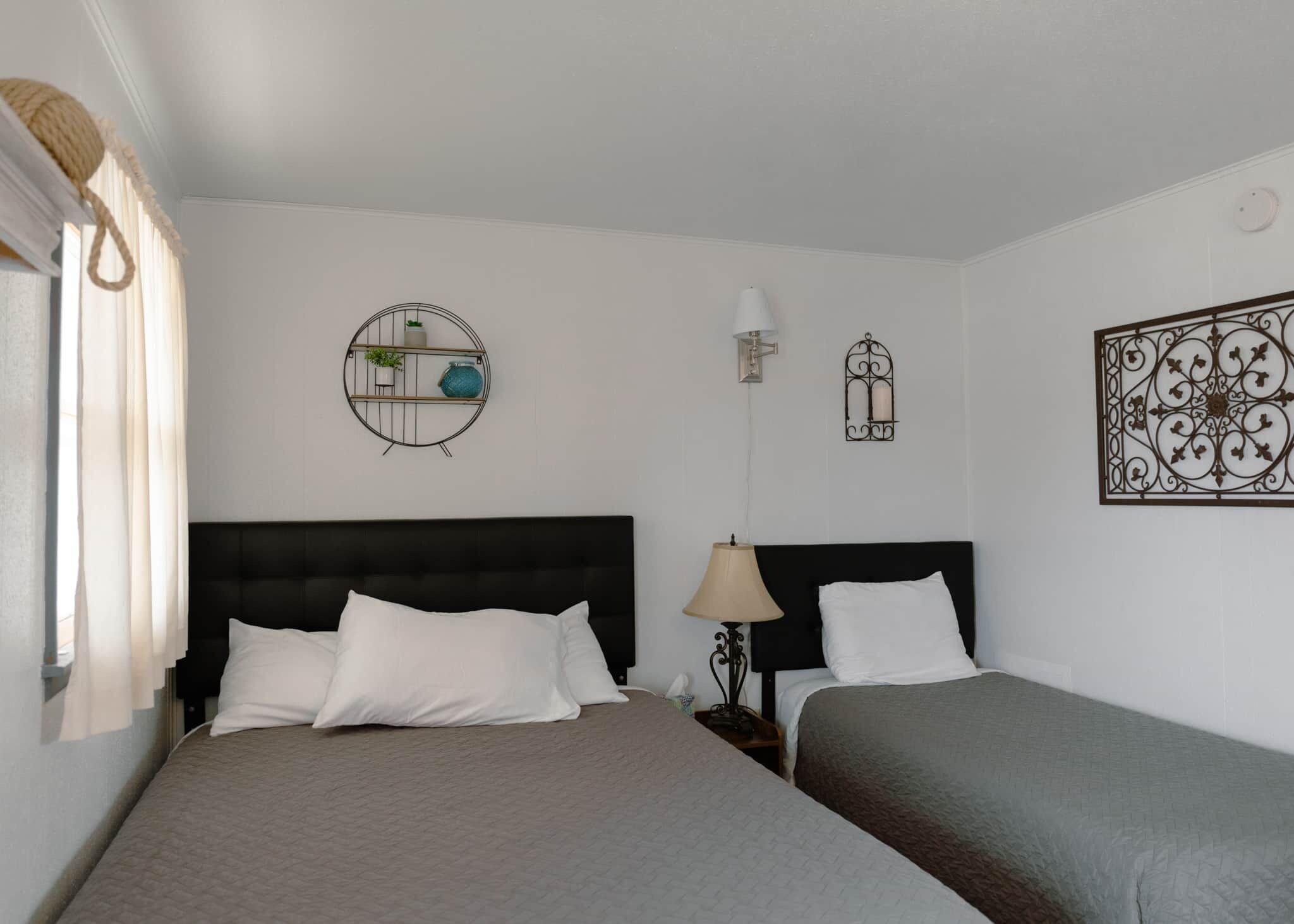 Een hotelkamer met twee bedden, een ronde wandplank met planten, een wandlamp en een decoratief metalen object.