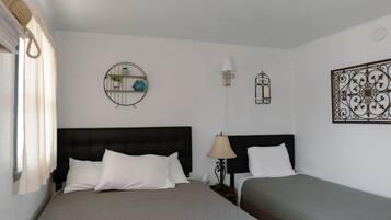 Een hotelkamer met twee bedden, een ronde wandplank met planten, een wandlamp en een decoratief metalen object.