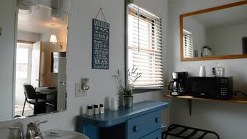Un baño con lavamanos, espejo y tocador azul con cajones.