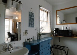 A bathroom with a sink, mirror, and a blue vanity with drawers.