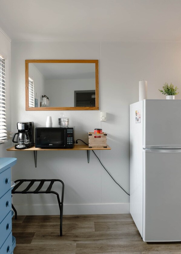 A compact kitchenette with a microwave, coffee maker, and a small refrigerator.