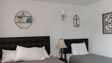 Une chambre d’hôtel avec deux lits, une étagère murale ronde ornée de plantes, une lampe fixée au mur et des œuvres d’art décoratives accrochées au mur.