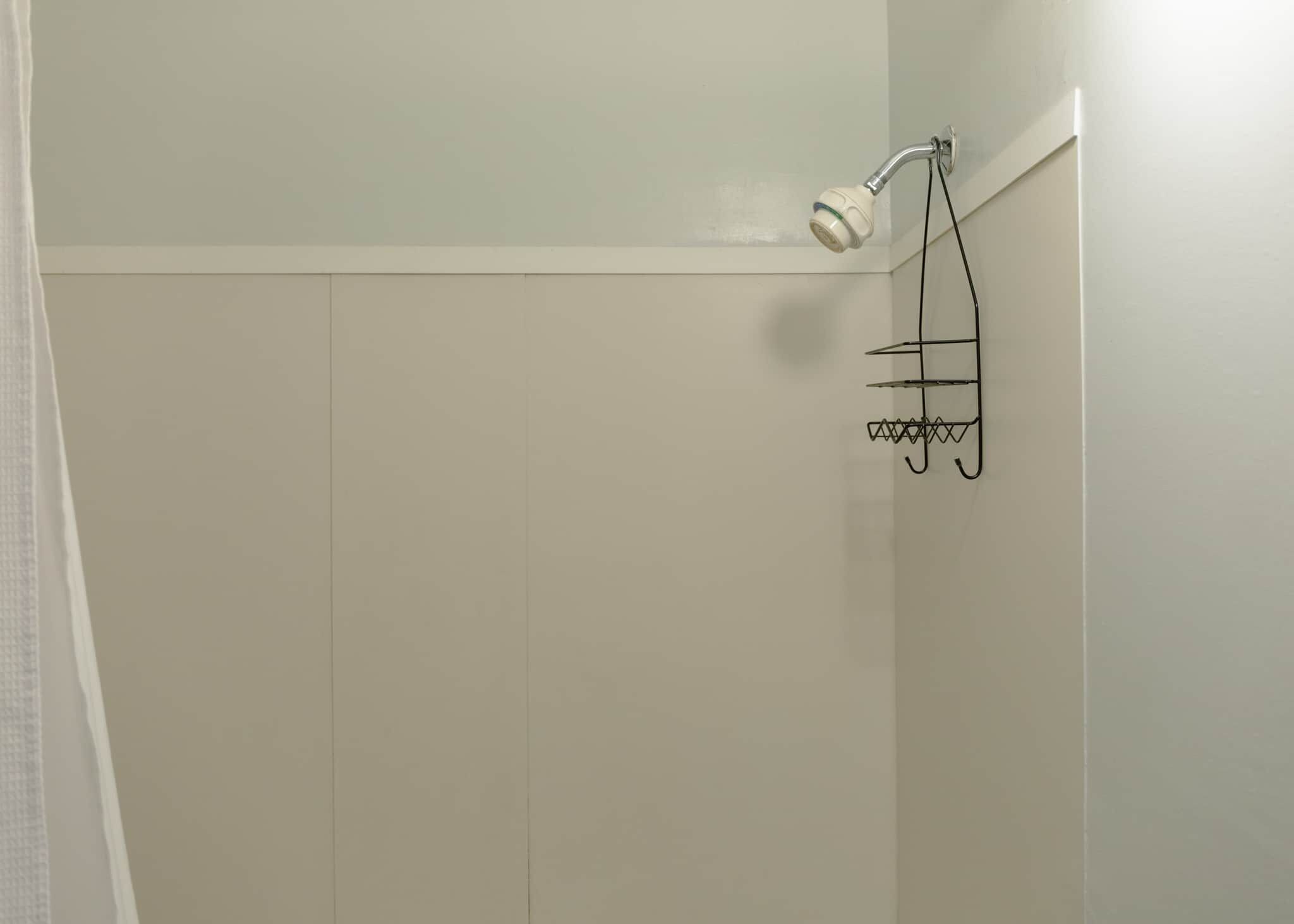 Een douche met een handdouche en een metalen handdoekrek.