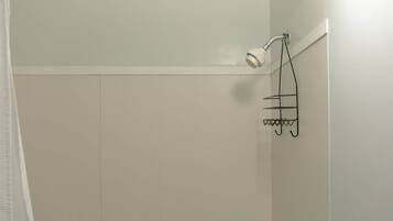 Een douche met een handdouche en een metalen handdoekrek.