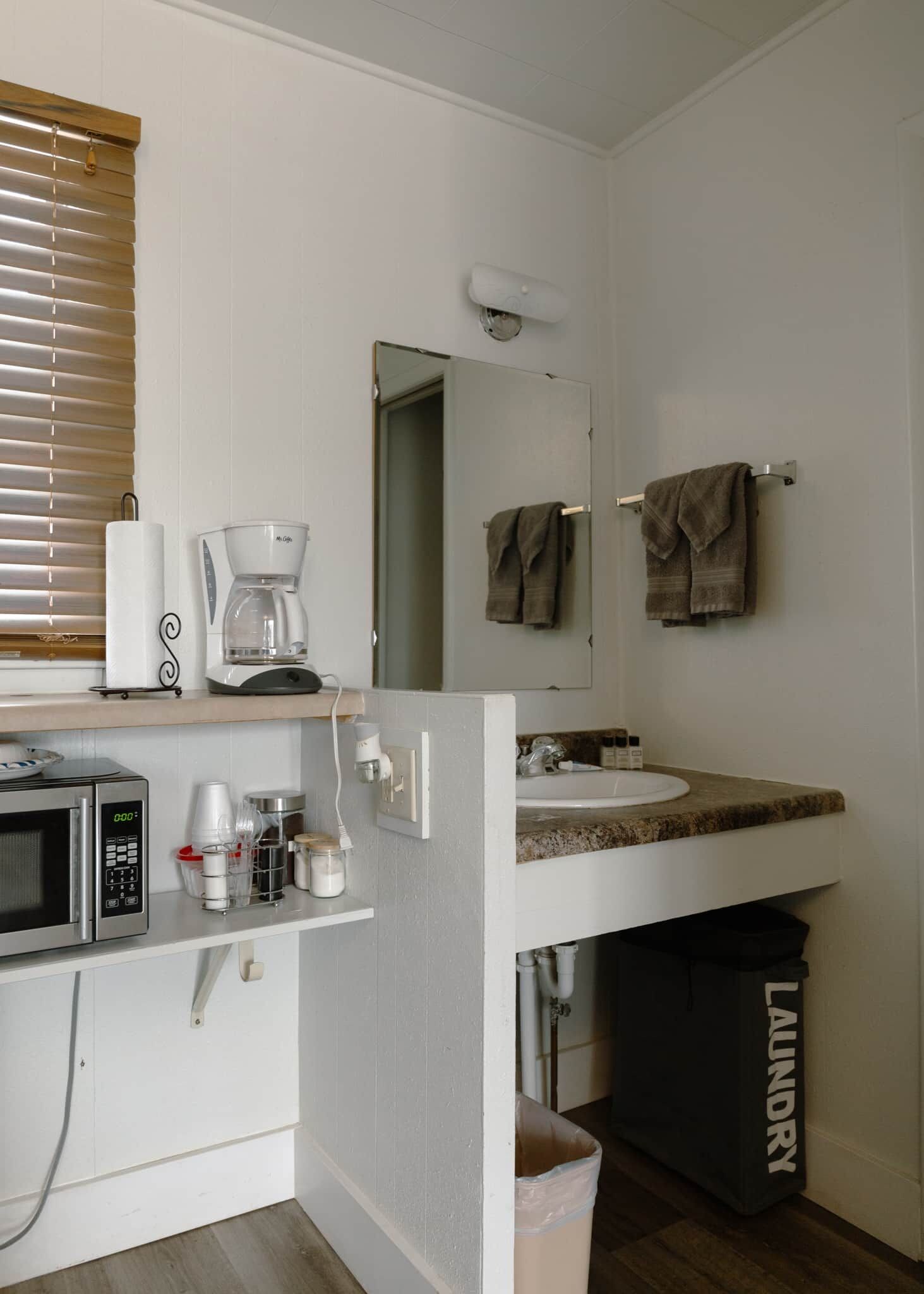 A compact kitchenette with a microwave, coffee maker, and storage containers.