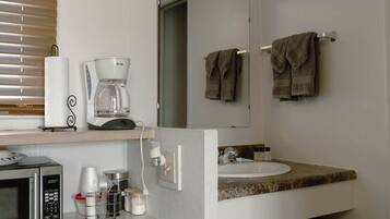 A compact kitchenette with a microwave, coffee maker, and storage containers.
