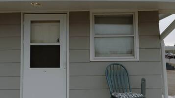 A house with a white door, a window, and a blue chair outside.