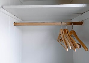 Un perchero de madera con varios colgadores de madera frente a una pared blanca.