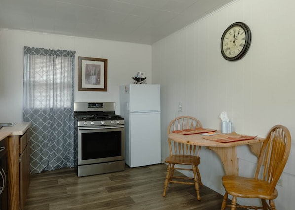 Une cuisine de taille réduite équipée d’une cuisinière, d’un four, d’un réfrigérateur et d’une table à manger avec des chaises.