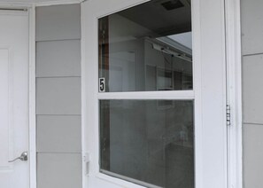 A white door with a number '5' on it, a window with a screen, and a white exterior wall.