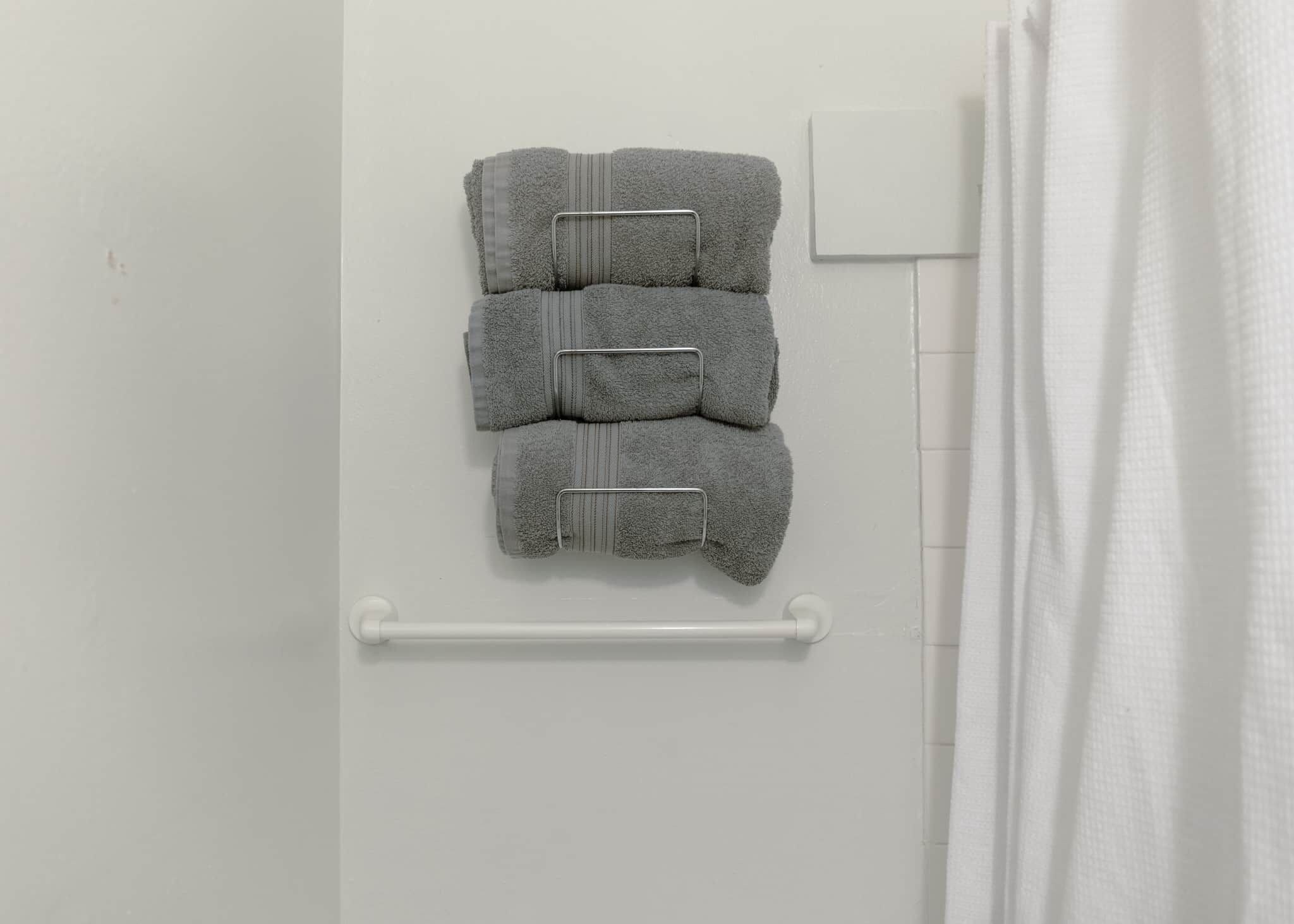 Une salle de bain avec un porte-serviettes sur lequel sont pliées trois serviettes.