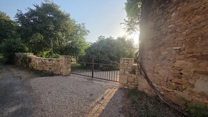 A gravel driveway leading to a gated entrance with stone walls and a metal gate. - Vacation rental in the Périgord Noir region between Périgueux and Sarlat, featuring a heated Nordic bath, (Granges-d'Ans)