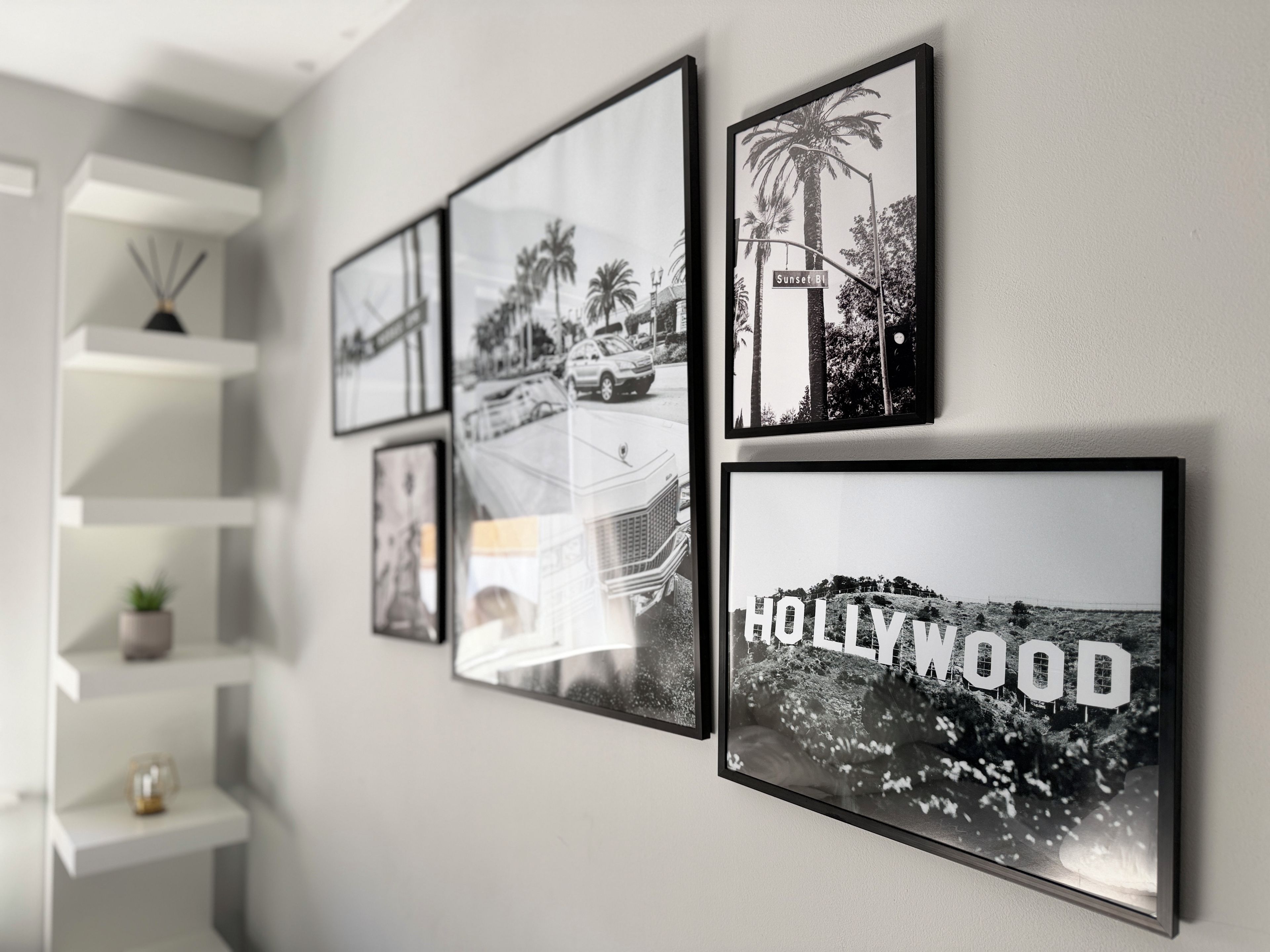 Eine Wand mit vier Schwarz-Weiß-Fotografien von Stadtansichten, darunter ein Auto auf der Sunset Boulevard und das Hollywood-Schild.