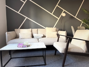 Ein modernes Wohnzimmer mit einer Couch, einem Couchtisch und einem Sessel.
