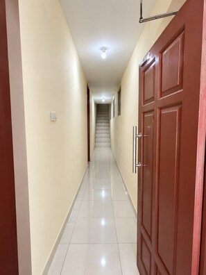 A hallway with a tiled floor, a door with a handle, and a light fixture on the ceiling. - Hotel O Pollux Mall Cikarang (Cikarang)