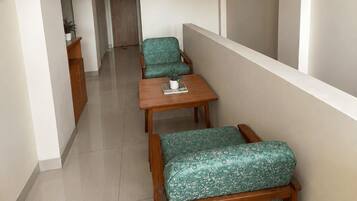A narrow corridor with a wooden bench and a small table, a door at the end, and a small potted plant on the table.