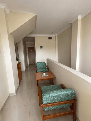 A narrow corridor with a wooden bench and a small table, a door at the end, and a small potted plant on the table. - Hotel O Pollux Mall Cikarang (Cikarang)