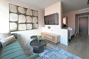 Una sala de estar moderna con un sofá seccional, una mesa de centro con una planta, un televisor de pantalla plana y un mueble consola minimalista.